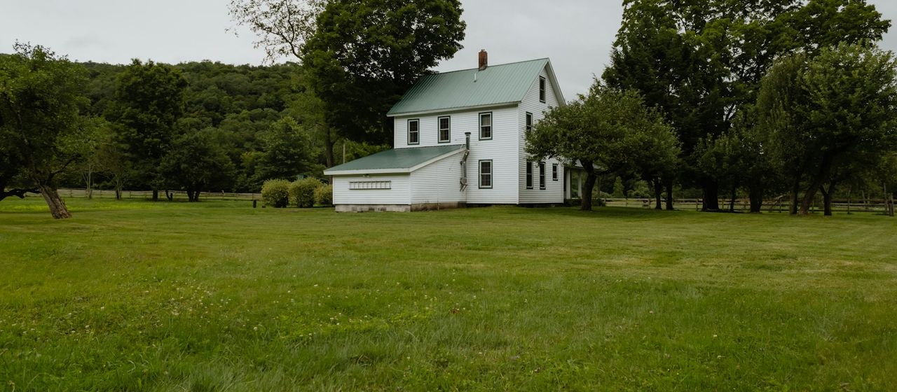 White farmhouse with a large lawn in rural New York
